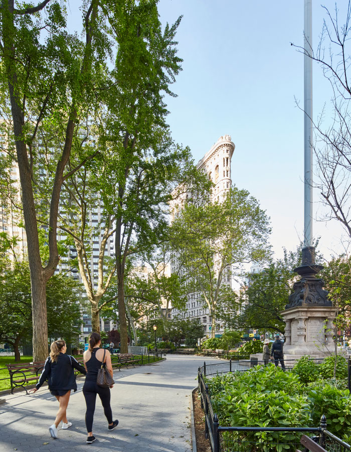 Two women walk down a pathway in Madison Square Park
