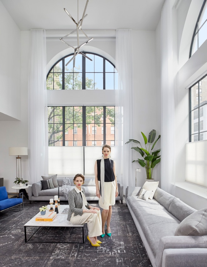 Two women in the furnished Maisonette corner living room with 20-foot arched windows at 90 Lex