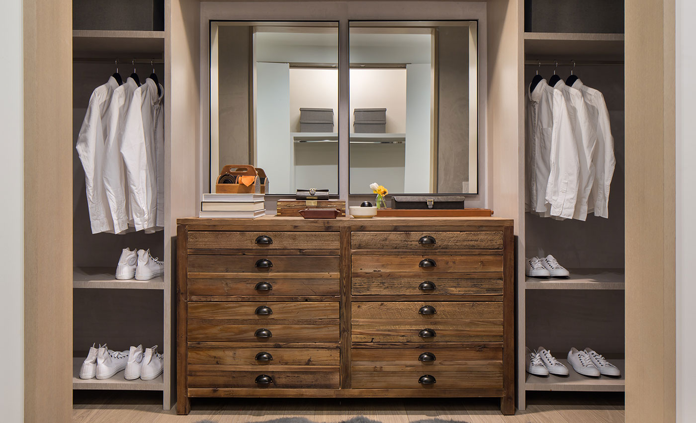 spacious closet furnished with dressers and two mirrors
