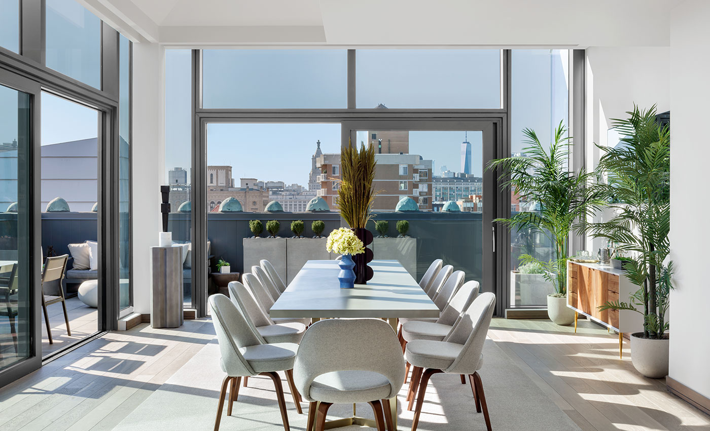 sun filled living space with large dining table and floor to ceiling windows